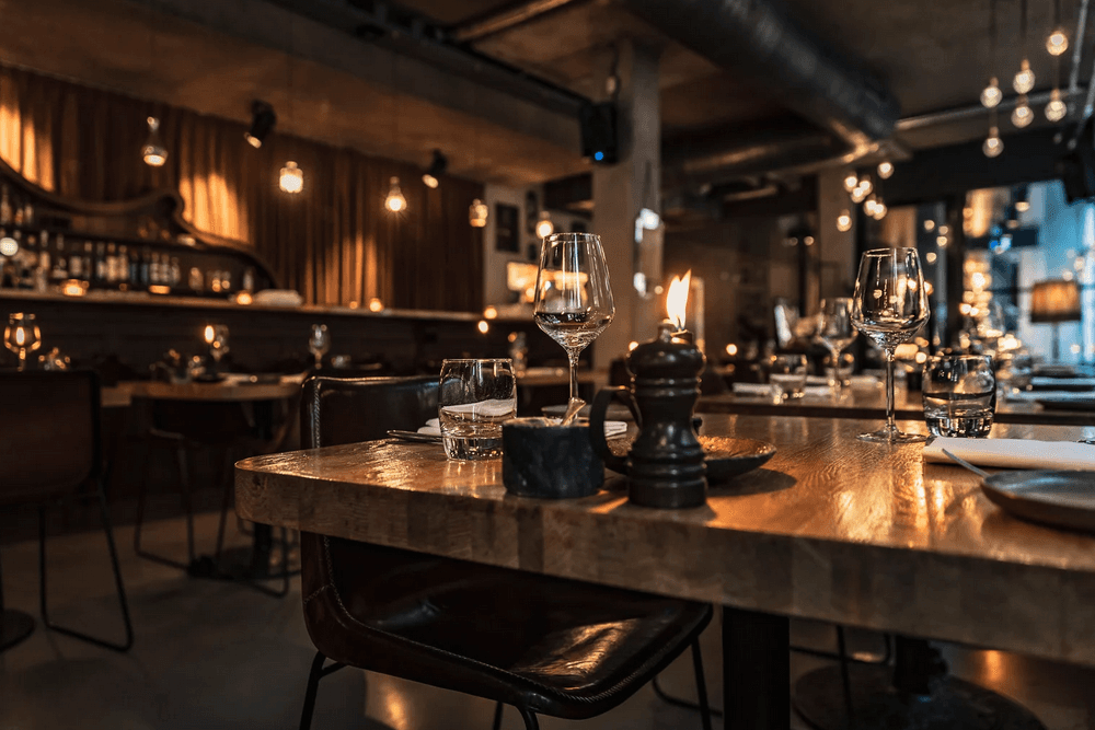 A beautifully dimly lit restaurant table set with glasses, candles, and rustic decor.