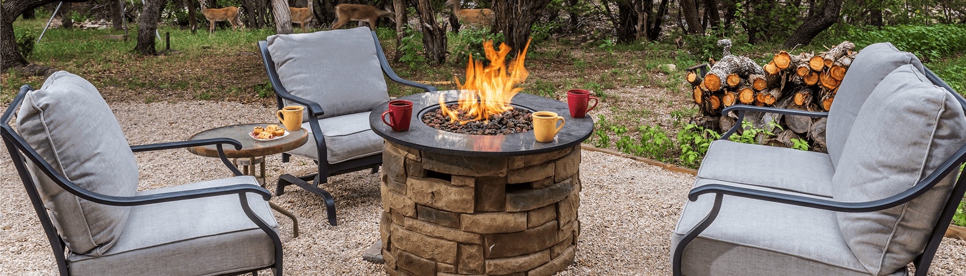A cozy outdoor seating area with two chairs around a fire pit, surrounded by nature.