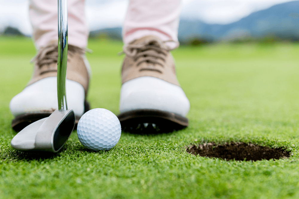 A golfer prepares to putt a white golf ball towards a hole on a green.