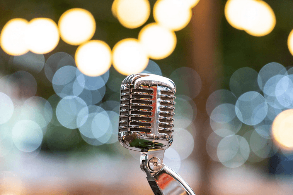 A close-up of a vintage microphone against a blurred, colorful bokeh background.