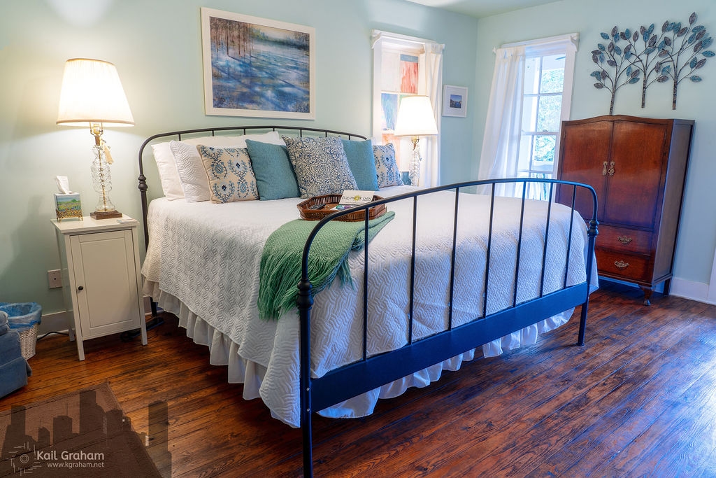 King-sized bed with white bedspread with soft green walls