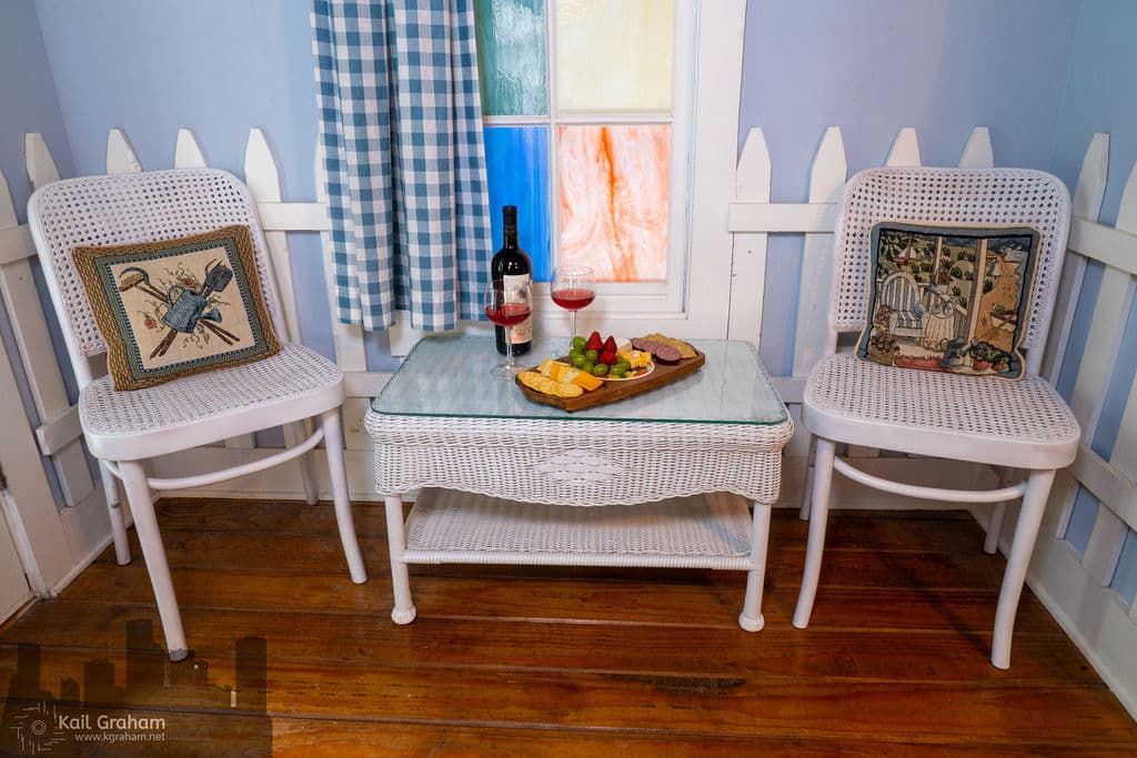 Wicker table and chairs with bottle of wine and cheese plater