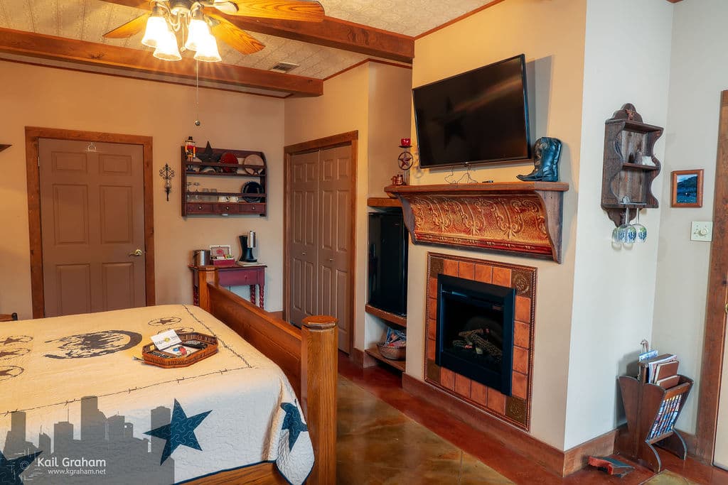 View of king-sized bed, flat screen TV, mini refrigerator and electric fireplace