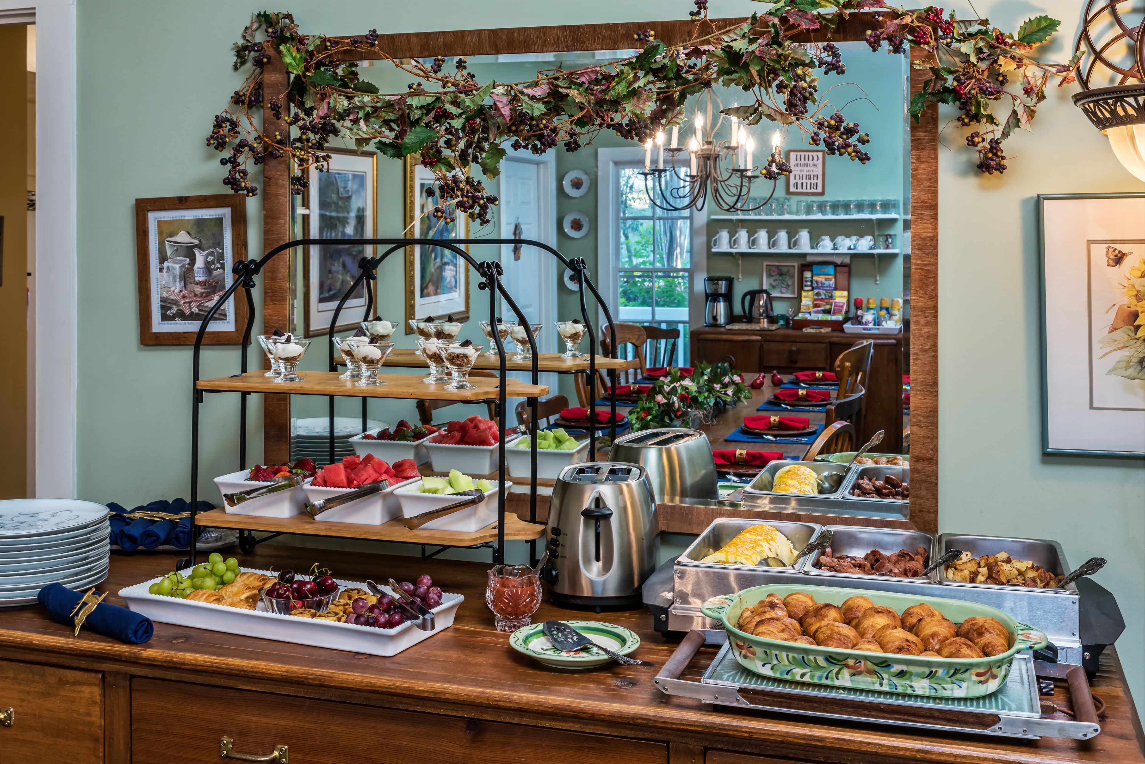 A beautifully arranged breakfast buffet featuring fruit, pastries, and various hot dishes in a charming dining setting.