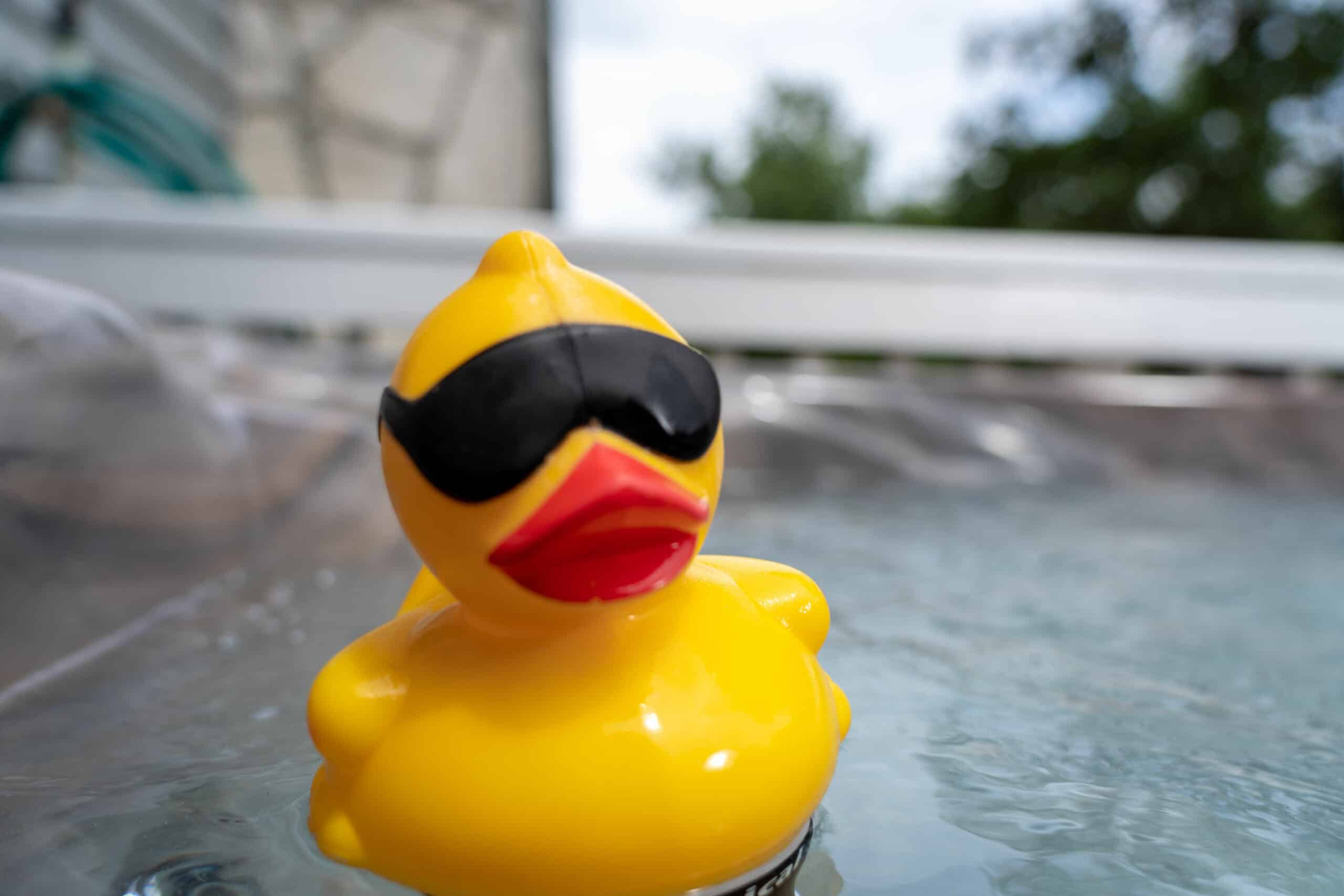 A cool yellow rubber duck wearing black sunglasses floats on water.