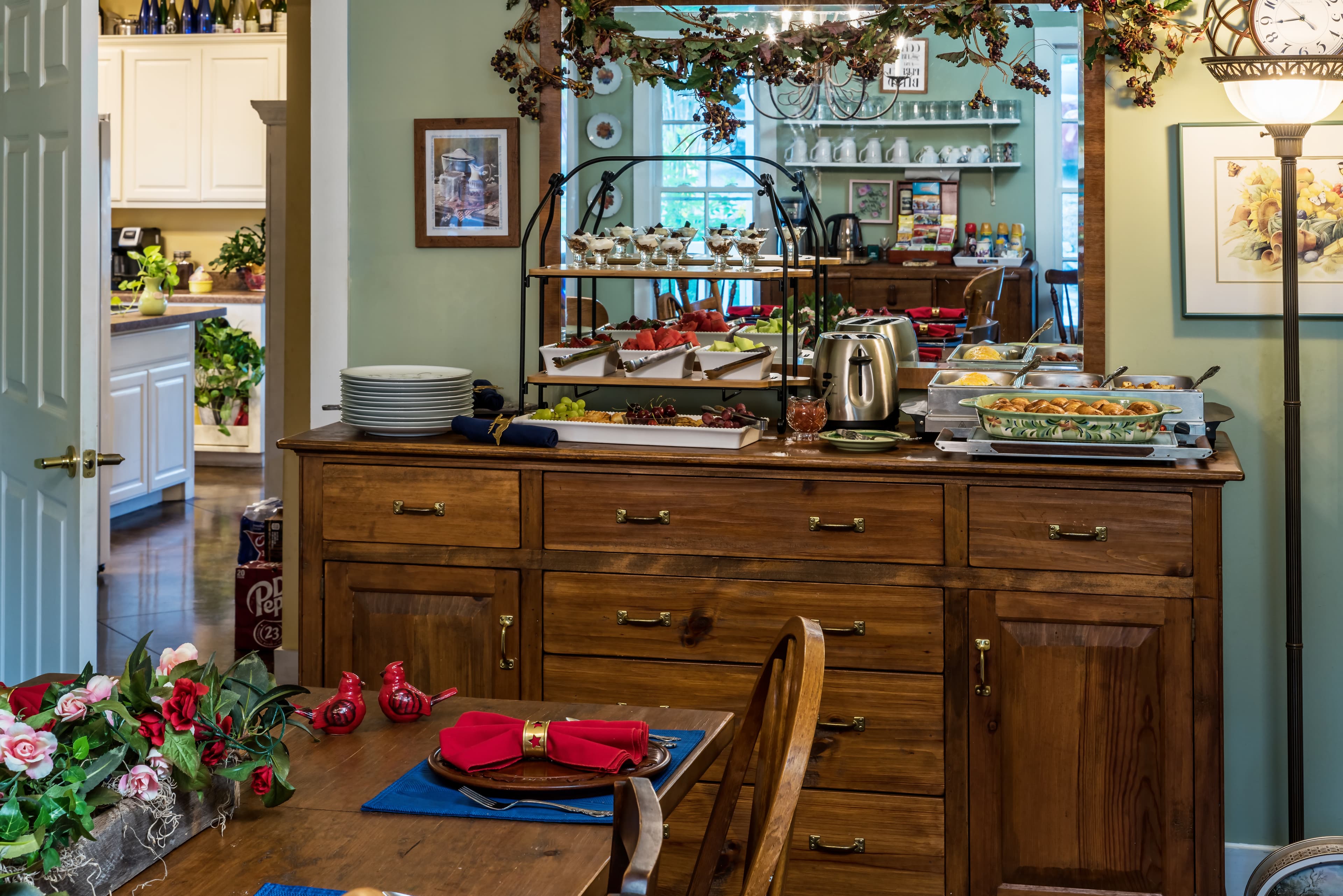 A cozy dining area with a wooden sideboard displaying food, plates, and decorative elements.